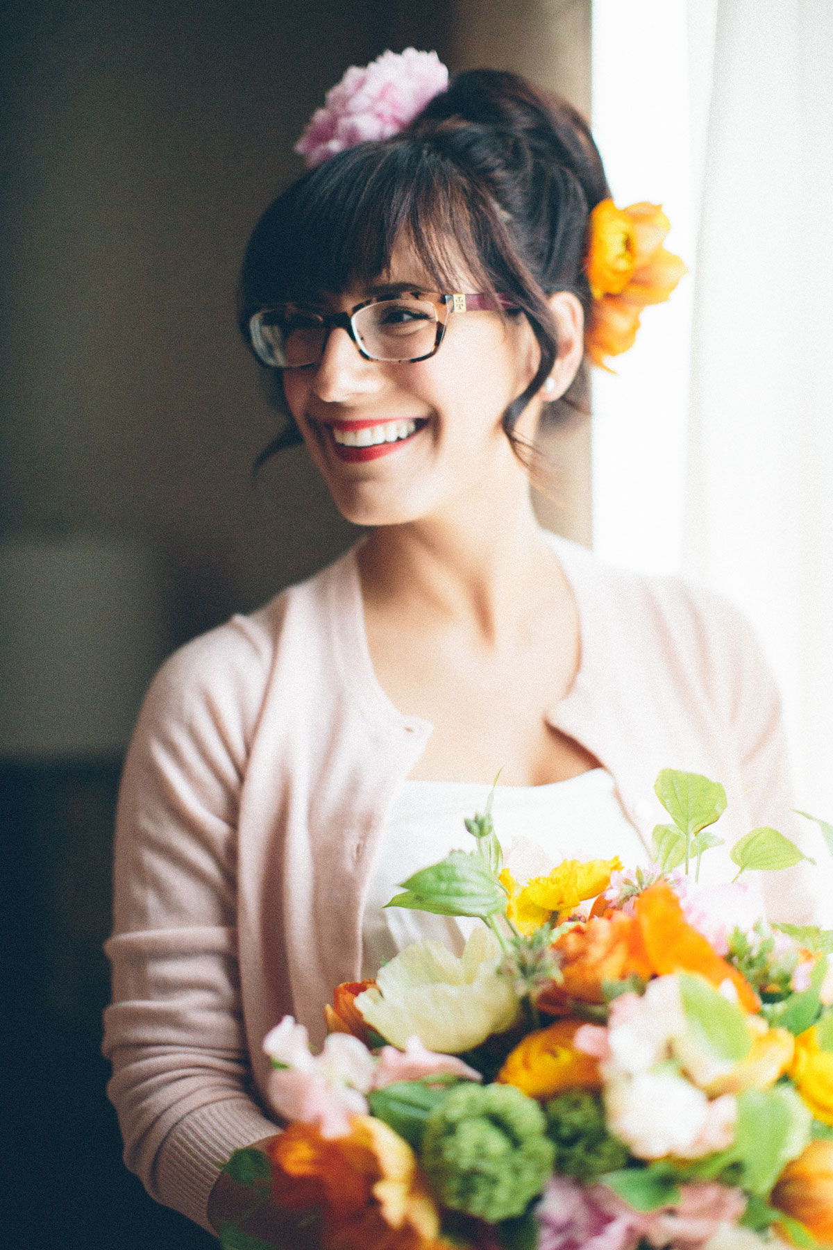 Portrait of a Boston Bride wearing a pink cardigan and orange flowers in her updo