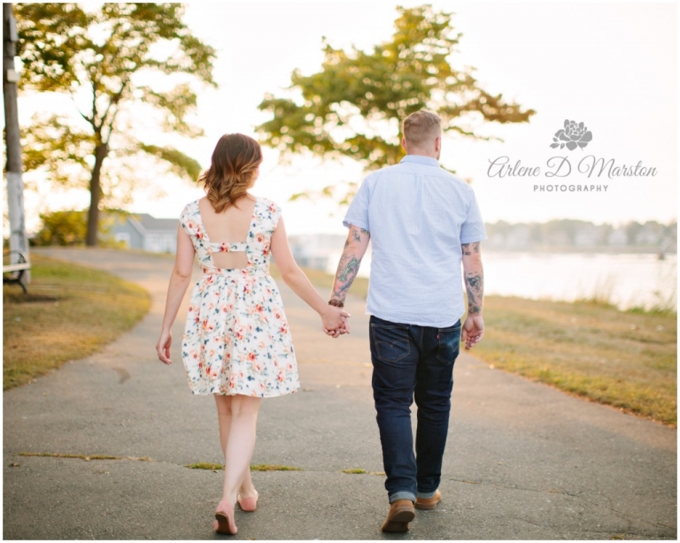 Engaged couple holding hands and walking through Salem Willows