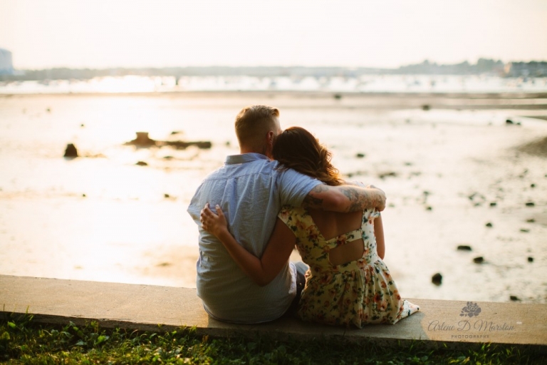 Engaged couple with arms around each other during sunset at Salem Willows