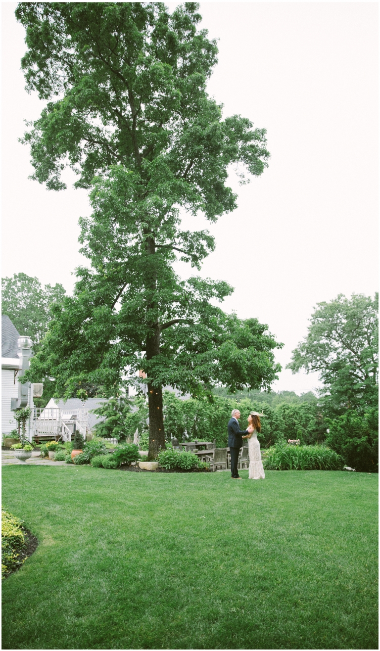 Bride and groom hold each others arms near a tall tree after their Herb Lyceum Wedding