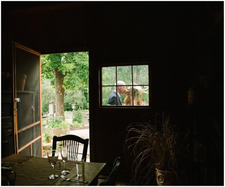 Bride and groom kissing in the window of the carriage house at Herb Lyceum