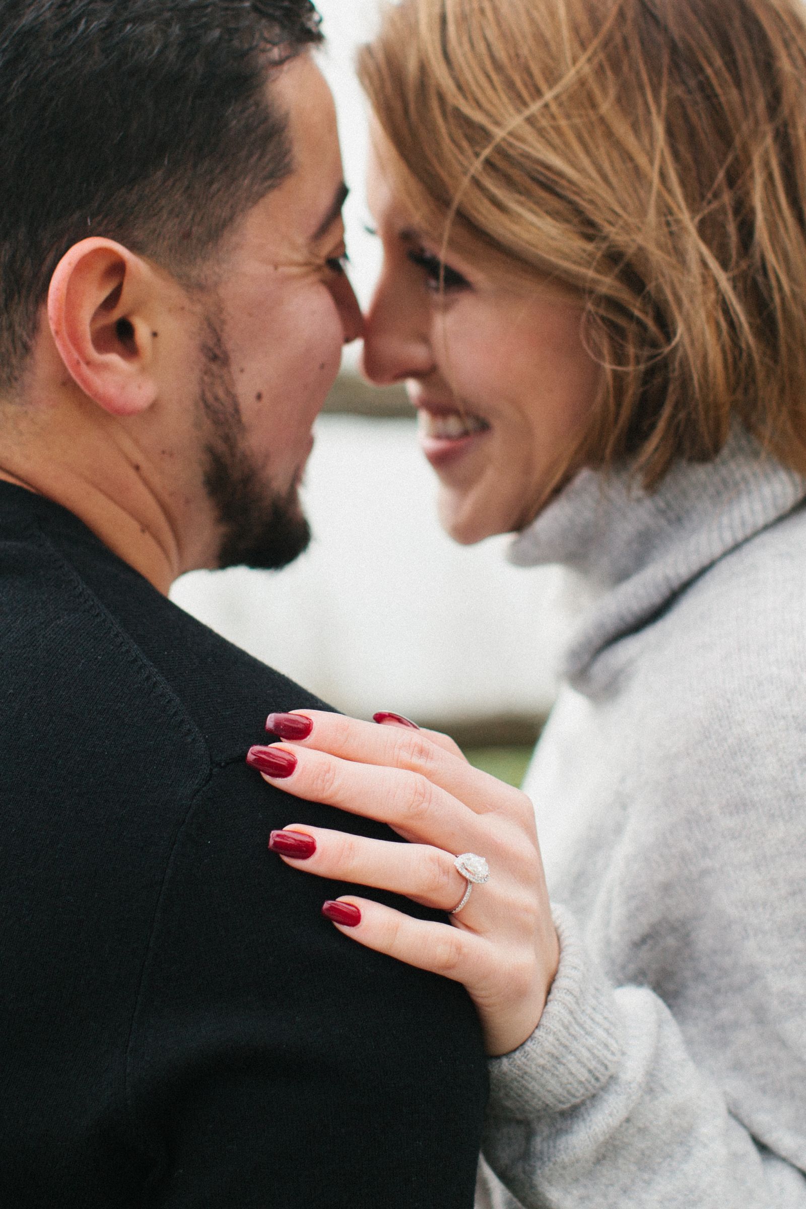 Close up the hands of a woman wearing a pear-shaped diamond engagement ring he received moments before taking this picture