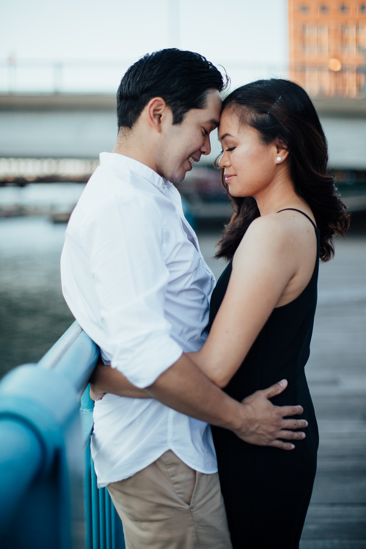 Filipino Couple hug along blue railings on Boston's Fort Point channel