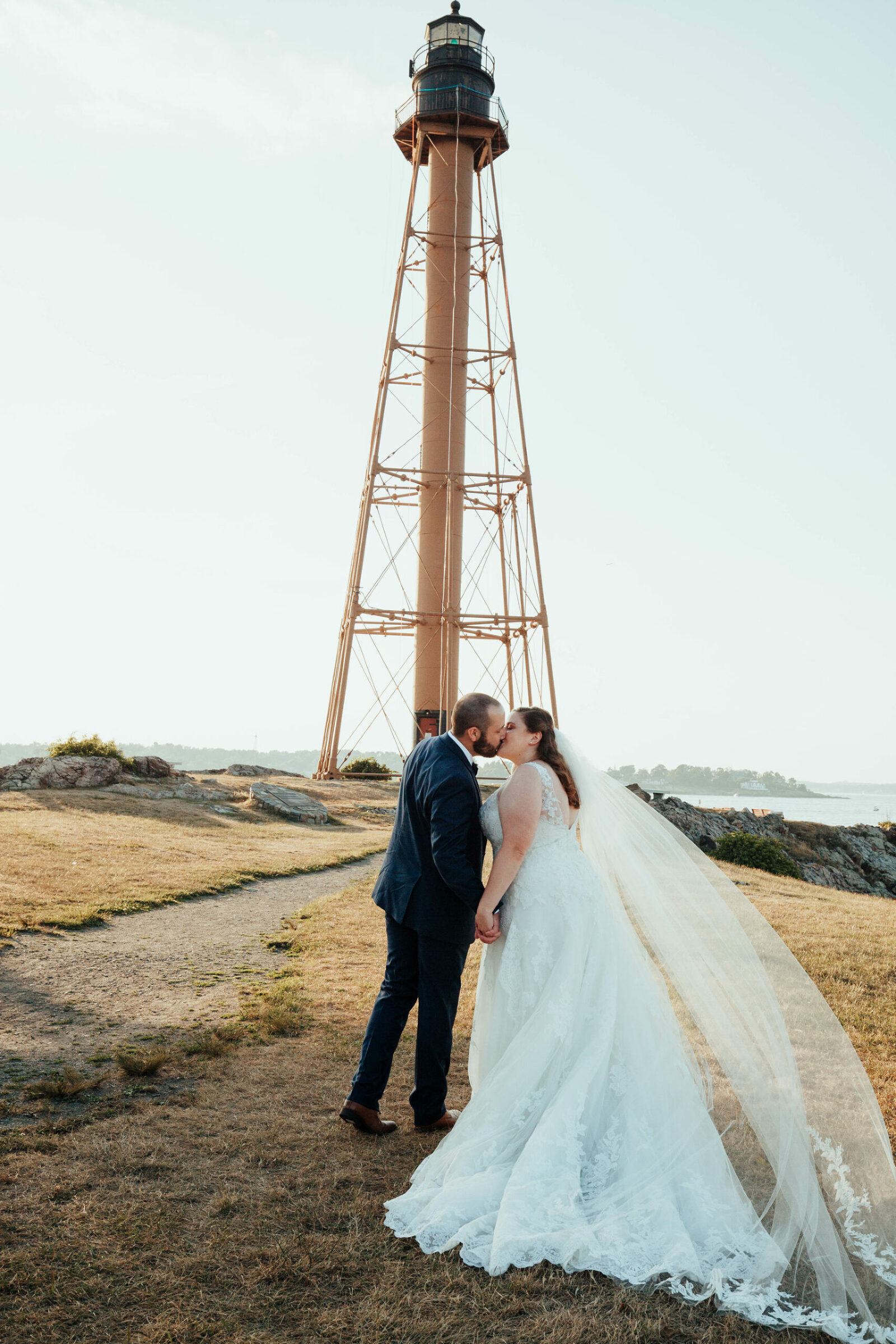 Bride and kiss near in front of Marblehead lighthouse at Chandler Hovey Park